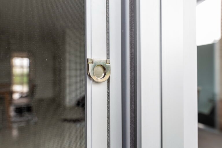 Nahaufnahme einer Insektenschutztür aus Aluminium mit Griffschlaufe und feinem Schutzgitter.